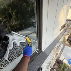 Technician washing a soapy window with a strip washer on a Tampa Bay home