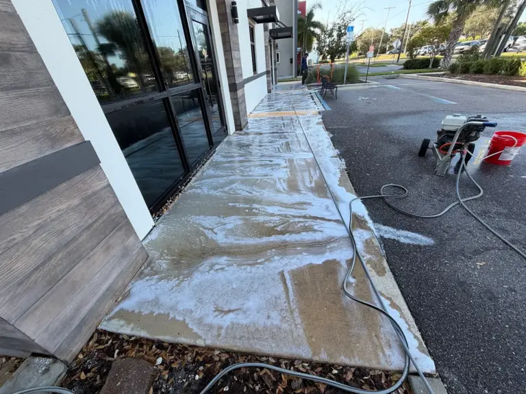 Washing the concrete walkway along the front of the building