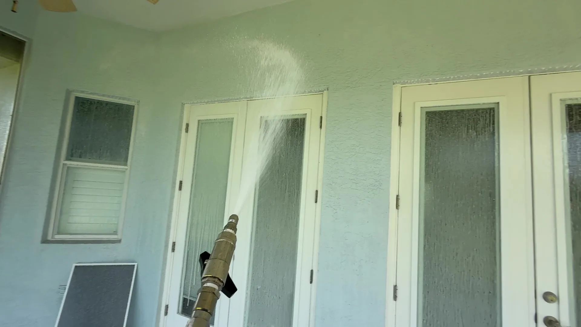Soft washing the stucco wall and French doors of a lanai in Tampa Bay