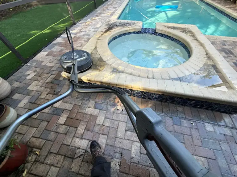 Rotary surface cleaner cleaning the brick paver pool deck next to the spa in Oldsmar, FL