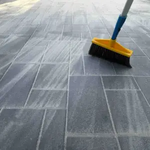 Sweeping polymeric sand into the joints of a paver patio