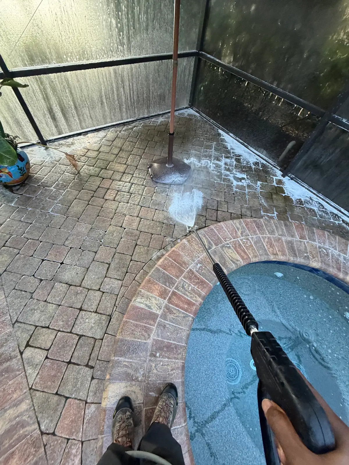 Rotary surface cleaner on the brick paver pool deck inside a pool cage in Safety Harbor, FL