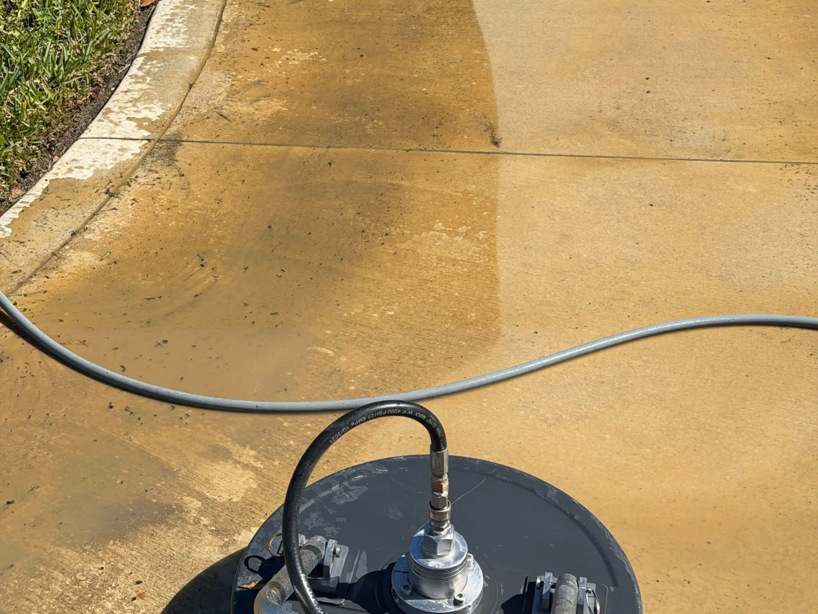 Surface cleaner leaving a clean stripe on a stained concrete driveway in Tampa, FL