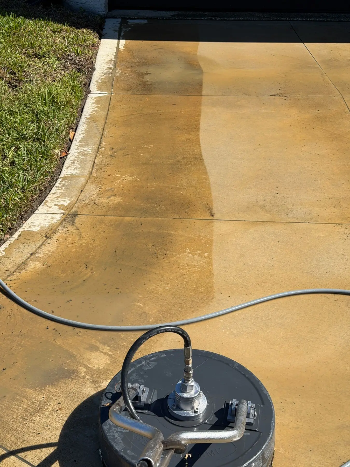 One surface-cleaner pass showing clean concrete next to stained concrete in Tampa, FL