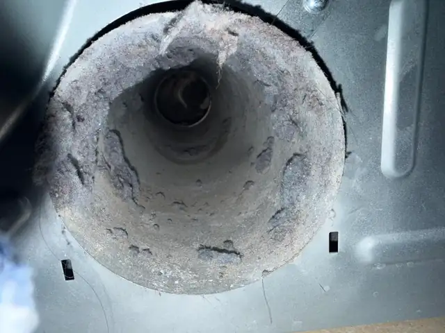 Lint and dust caked inside the opening of a dryer duct, before cleaning