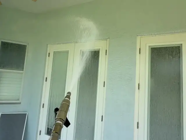 Soft washing the stucco wall and French doors of a lanai in Tampa Bay